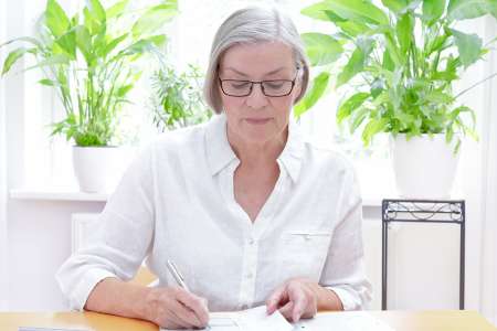 Foto: Ältere Dame bearbeitet Unterlagen